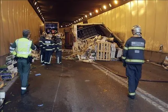 Unos bomberos trabajan en el túnel de acceso a Algeciras (Cádiz) donde esta mañana ha fallecido una persona en un accidente de tráfico cuando un camión de origen marroquí que transportaba fruta y verdura se salió de la vía, volcó e impactó contra cuatro vehículos uno de los cuáles quedó bajo el remolque. EFE